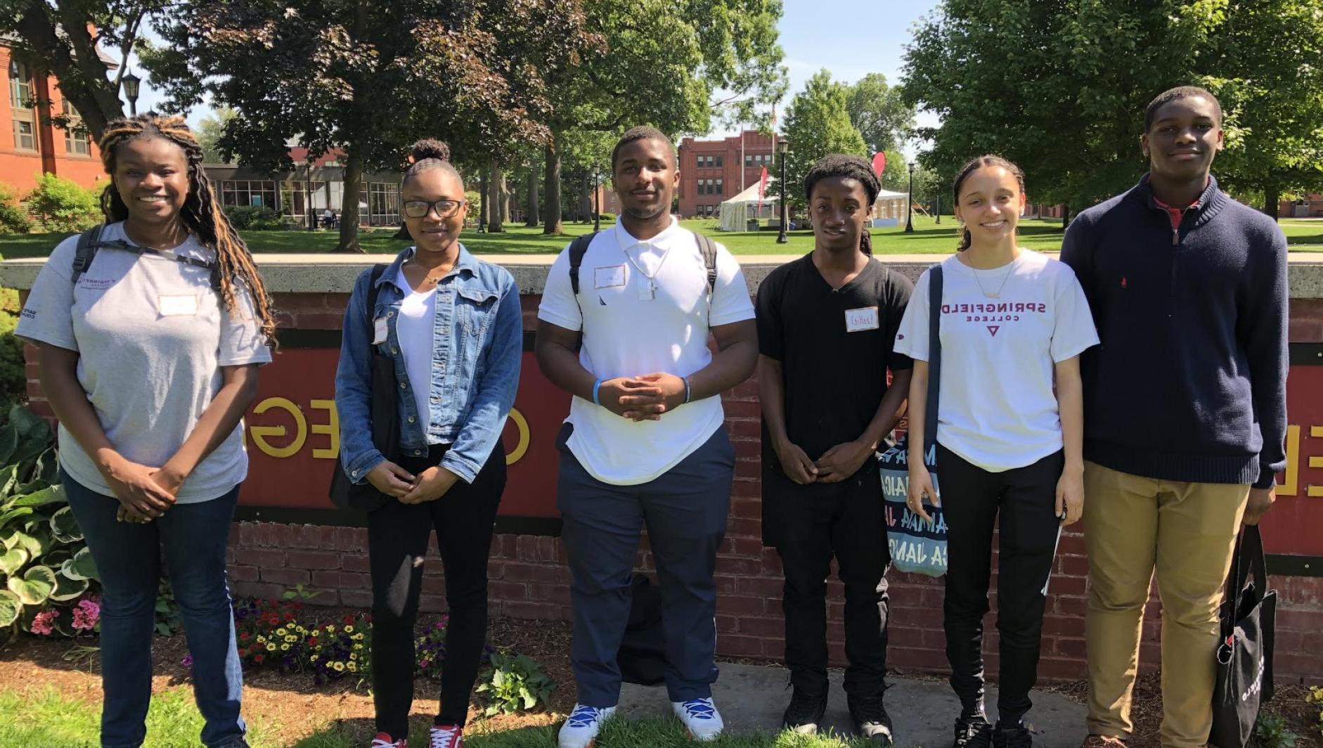 Student workers stand in front of the Springfield College sign. 