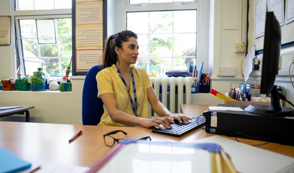 A close-up of a young female teacher sitting at her desk and preparing her lesson for the day. 